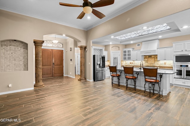 14624 Long Shadow Ave, El Paso, TX 79938 - kitchen featuring appliances with stainless steel finishes, custom exhaust hood, ornate columns, a breakfast bar area, and arched walkways