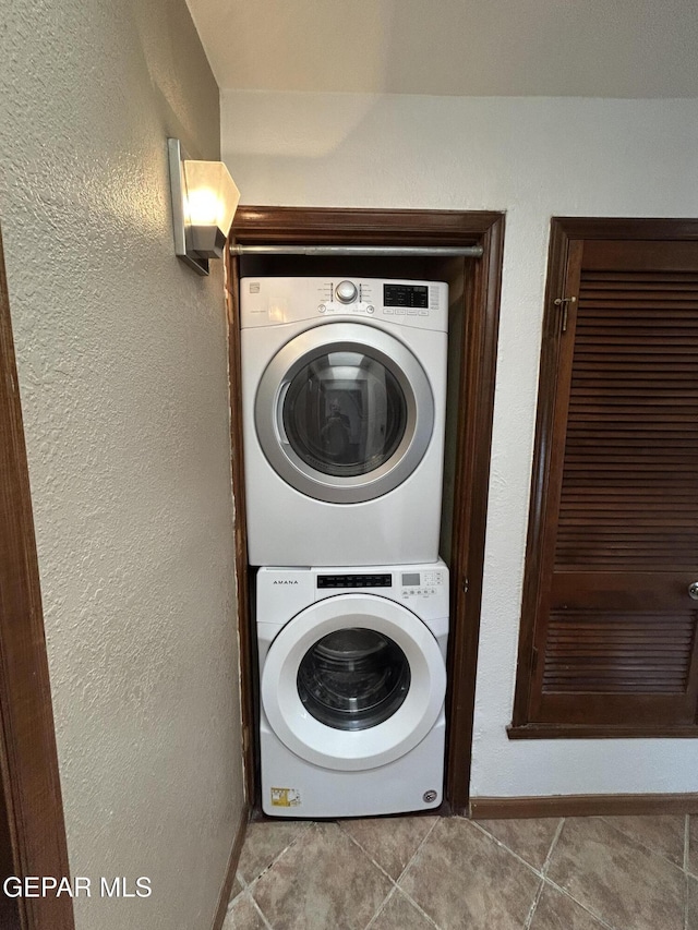 6061 Bridalveil Dr, El Paso, TX 79924 - laundry room with stacked washing machine and dryer, tile patterned floors, and baseboards