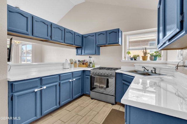 13324 Mitchell Dr, Horizon City, TX 79928 - kitchen with stainless steel range with gas stovetop, blue cabinetry, a sink, vaulted ceiling, and plenty of natural light