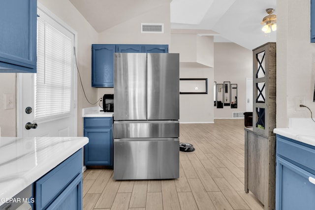 13324 Mitchell Dr, Horizon City, TX 79928 - kitchen with freestanding refrigerator, blue cabinetry, light wood-type flooring, vaulted ceiling, and ceiling fan
