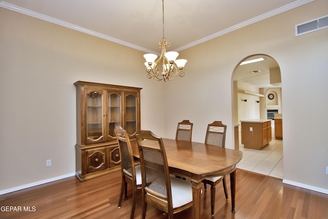 216 Desert Garden Dr, Santa Teresa, NM 88008 - dining room featuring crown molding, arched walkways, light wood-type flooring, a chandelier, and baseboards