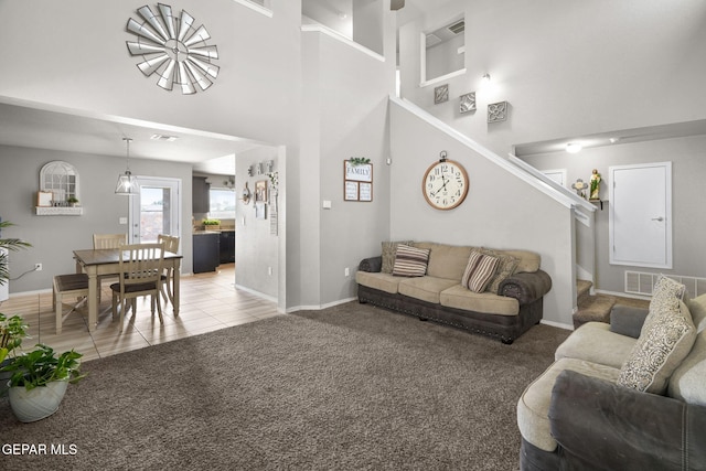 11562 Flor Gloriosa Dr, Socorro, TX 79927 - living area featuring a high ceiling, stairs, baseboards, light carpet, and light tile patterned floors