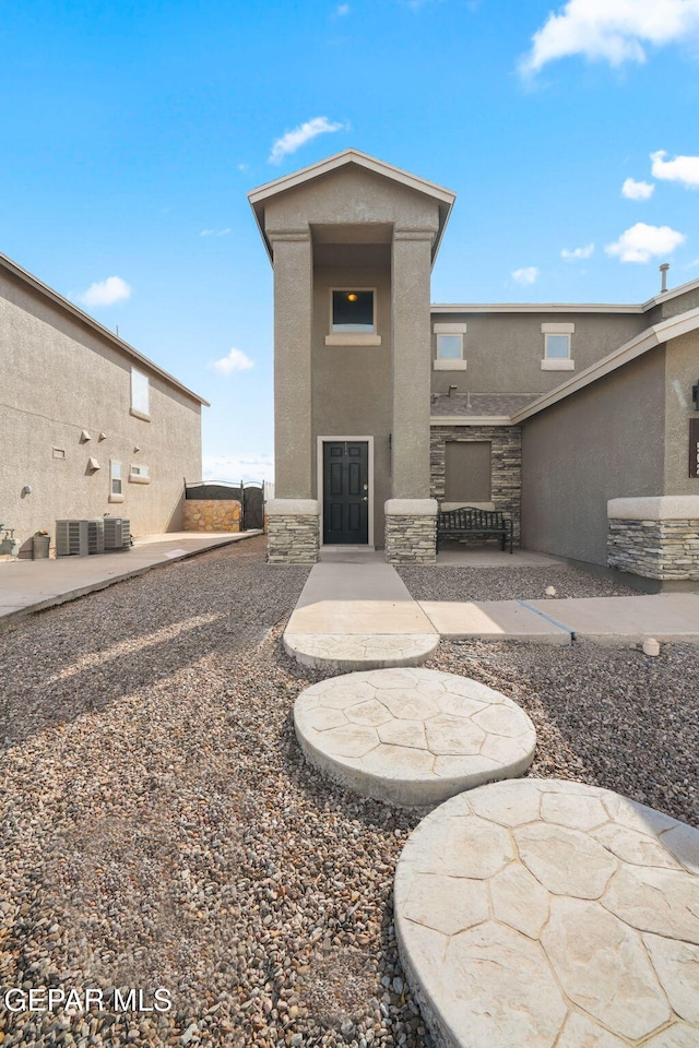 11562 Flor Gloriosa Dr, Socorro, TX 79927 - back of house featuring stucco siding, stone siding, a patio, and central air condition unit