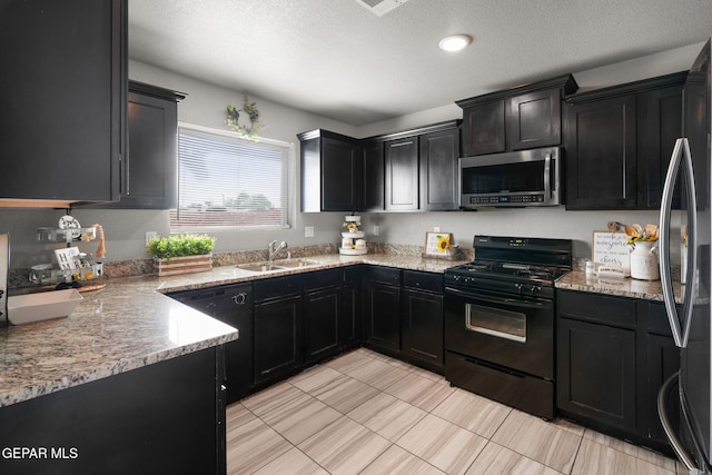 11562 Flor Gloriosa Dr, Socorro, TX 79927 - kitchen with stainless steel microwave, gas stove, a sink, dark cabinets, and a textured ceiling