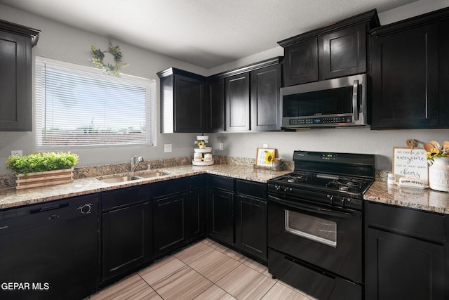 11562 Flor Gloriosa Dr, Socorro, TX 79927 - kitchen featuring black appliances, dark cabinetry, a sink, light stone counters, and light tile patterned floors