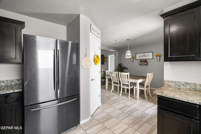 11562 Flor Gloriosa Dr, Socorro, TX 79927 - kitchen with freestanding refrigerator, light countertops, baseboards, dark cabinets, and decorative light fixtures