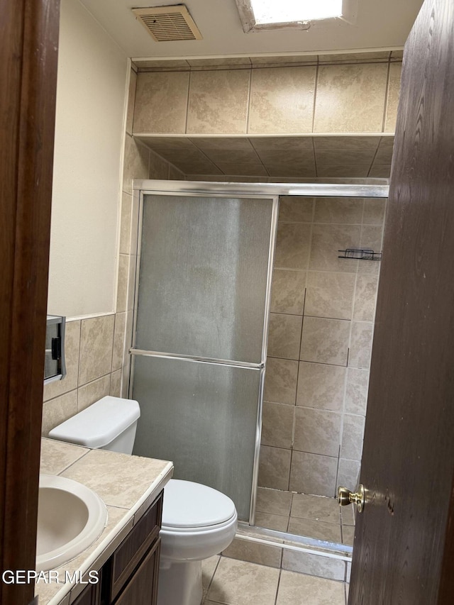 3910 Quasar Ct, El Paso, TX 79904 - full bathroom featuring toilet, vanity, tile walls, a stall shower, and tile patterned floors