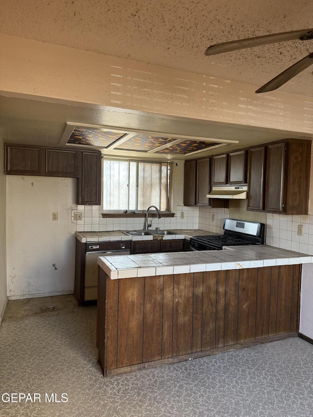 3910 Quasar Ct, El Paso, TX 79904 - kitchen with stainless steel range with gas cooktop, under cabinet range hood, tile counters, and dark brown cabinets