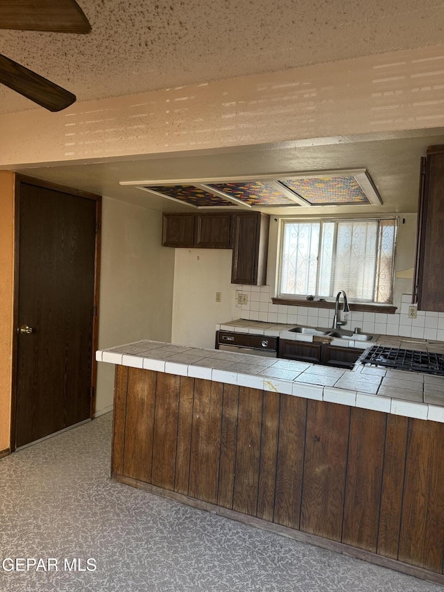 3910 Quasar Ct, El Paso, TX 79904 - kitchen featuring tile countertops, a sink, backsplash, and dark brown cabinets