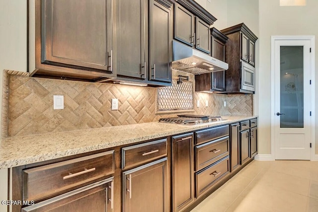 1861 War Path Dr, El Paso, TX 79911 - kitchen with under cabinet range hood, appliances with stainless steel finishes, light tile patterned flooring, light stone counters, and backsplash