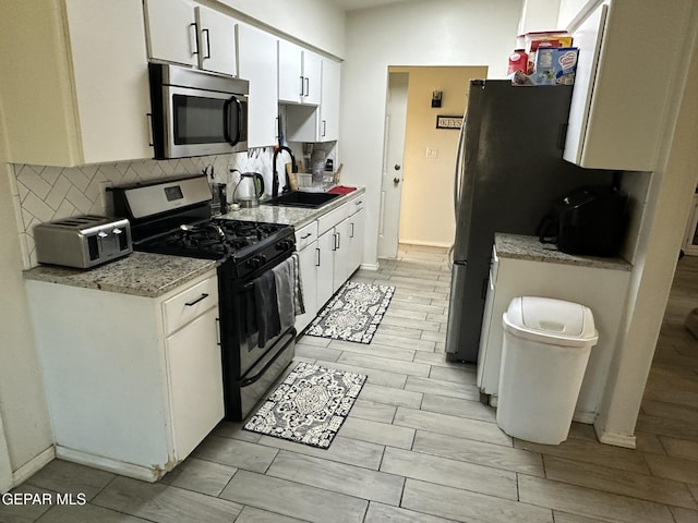 5028 Sagittarius Ave, El Paso, TX 79924 - kitchen with appliances with stainless steel finishes, a sink, white cabinets, and decorative backsplash