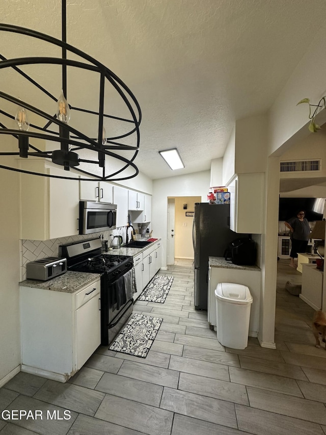 5028 Sagittarius Ave, El Paso, TX 79924 - kitchen with stainless steel appliances, white cabinetry, a sink, a textured ceiling, and wood finish floors