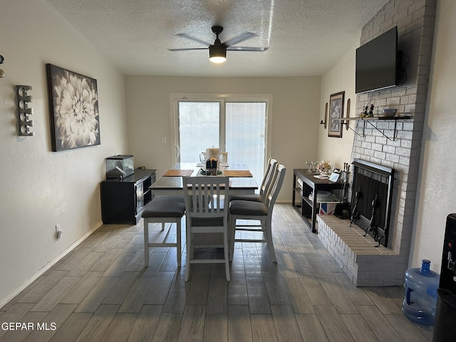5028 Sagittarius Ave, El Paso, TX 79924 - dining space with ceiling fan, dark wood-type flooring, a textured ceiling, baseboards, and a brick fireplace