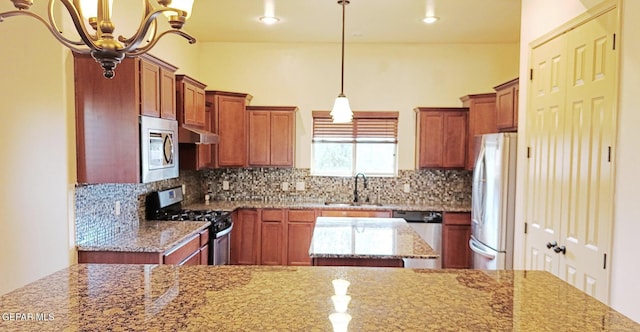 6065 Via De Los Arboles, El Paso, TX 79932 - kitchen with stainless steel appliances, a sink, brown cabinetry, light stone counters, and decorative backsplash