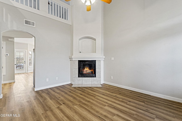 5965 Katelyn Gray Cir, El Paso, TX 79924 - unfurnished living room with a ceiling fan, wood finished floors, arched walkways, a high ceiling, and baseboards