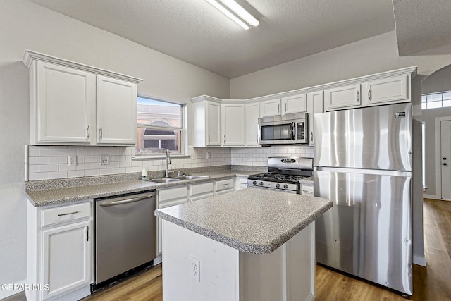 5965 Katelyn Gray Cir, El Paso, TX 79924 - kitchen featuring appliances with stainless steel finishes, a sink, wood finished floors, decorative backsplash, and white cabinetry