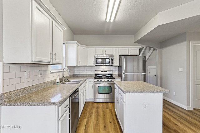 5965 Katelyn Gray Cir, El Paso, TX 79924 - kitchen with stainless steel appliances, a sink, light wood-type flooring, a kitchen island, and a textured ceiling