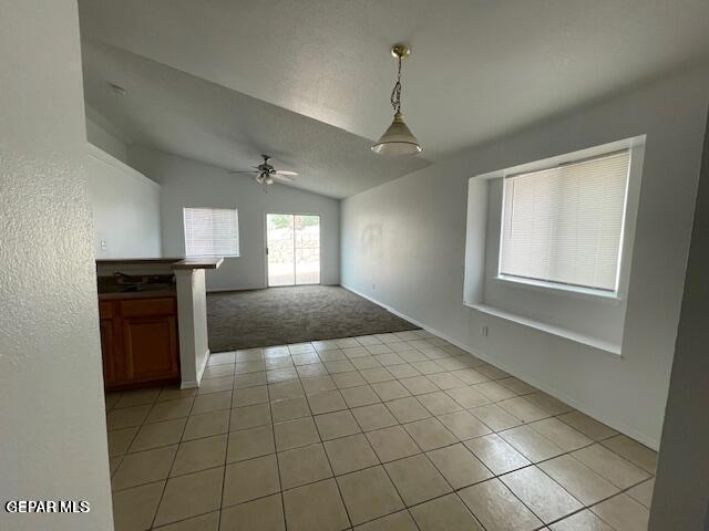 12501 Sombra Fuerte Dr, El Paso, TX 79938 - unfurnished dining area featuring lofted ceiling, ceiling fan, light colored carpet, light tile patterned floors, and baseboards