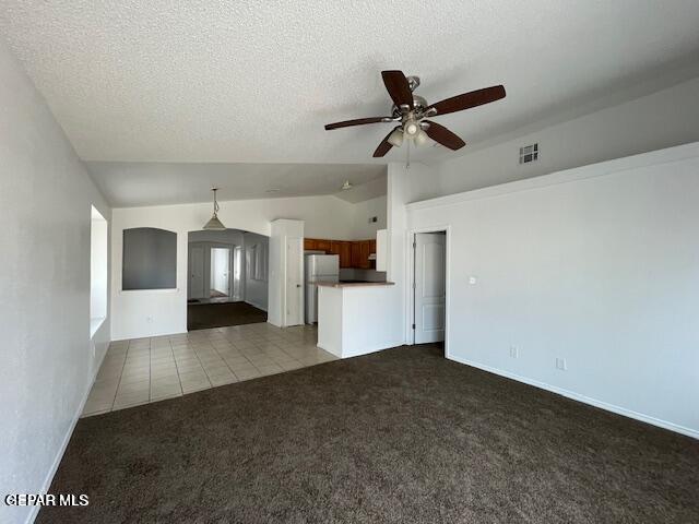 12501 Sombra Fuerte Dr, El Paso, TX 79938 - unfurnished living room featuring dark carpet, lofted ceiling, a ceiling fan, a textured ceiling, and dark tile patterned flooring