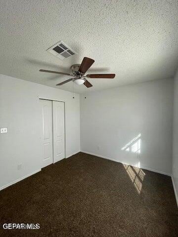 12501 Sombra Fuerte Dr, El Paso, TX 79938 - unfurnished bedroom featuring a closet, a textured ceiling, dark carpet, ceiling fan, and baseboards