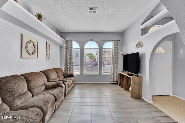 14156 Warren Belin Dr, Horizon City, TX 79928 - living area featuring light tile patterned floors, arched walkways, a textured ceiling, a textured wall, and baseboards