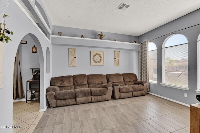 14156 Warren Belin Dr, Horizon City, TX 79928 - living room with arched walkways, a textured ceiling, and baseboards