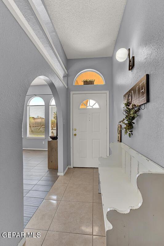 14156 Warren Belin Dr, Horizon City, TX 79928 - entryway with arched walkways, light tile patterned flooring, a textured ceiling, and a textured wall