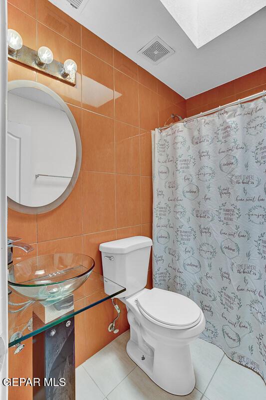 14156 Warren Belin Dr, Horizon City, TX 79928 - bathroom featuring tile walls, tile patterned floors, toilet, vanity, and a shower with curtain