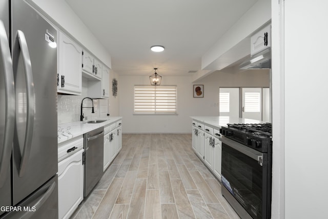6608 Los Altos Dr, El Paso, TX 79912 - kitchen with appliances with stainless steel finishes, a sink, under cabinet range hood, white cabinetry, and light wood-style floors