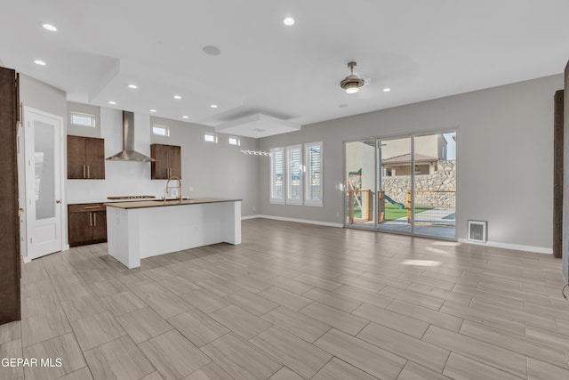2174 Enchanted Crest Dr, El Paso, TX 79911 - kitchen with wall chimney range hood, open floor plan, recessed lighting, dark brown cabinets, and baseboards