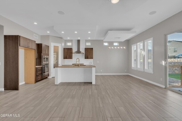 2174 Enchanted Crest Dr, El Paso, TX 79911 - kitchen with wall chimney exhaust hood, appliances with stainless steel finishes, a sink, open floor plan, and baseboards
