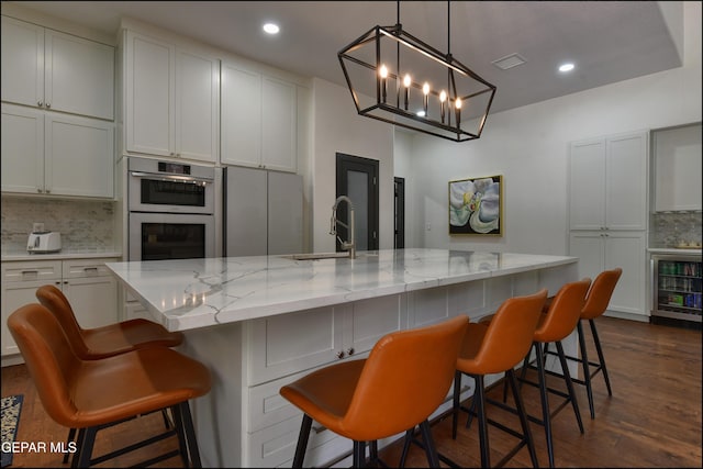 4490 Shadow Willow Dr, El Paso, TX 79922 - kitchen featuring beverage cooler, double oven, a sink, backsplash, and light stone counters