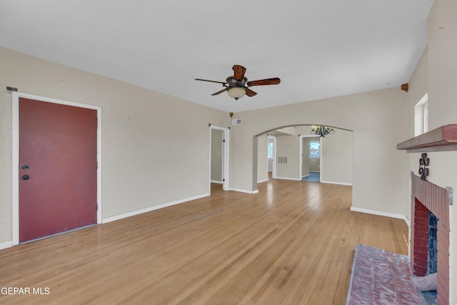 2312 Grant Ave, El Paso, TX 79930 - unfurnished living room with a fireplace, light wood-type flooring, ceiling fan, arched walkways, and baseboards