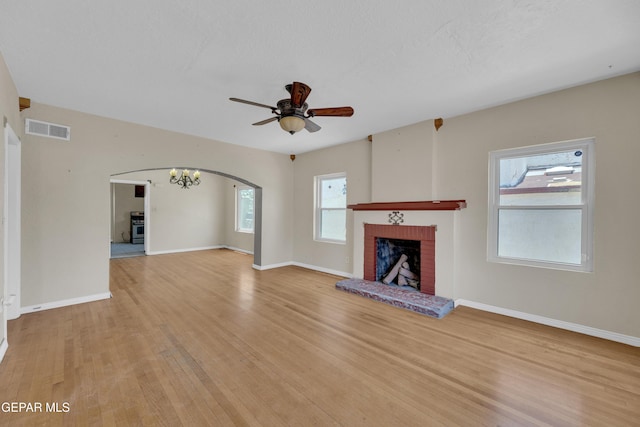 2312 Grant Ave, El Paso, TX 79930 - unfurnished living room featuring light wood-style flooring, arched walkways, a brick fireplace, ceiling fan, and baseboards