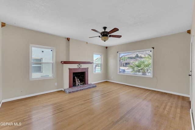 2312 Grant Ave, El Paso, TX 79930 - unfurnished living room with light wood-style floors, a brick fireplace, a ceiling fan, and baseboards