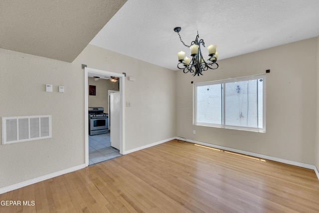 2312 Grant Ave, El Paso, TX 79930 - empty room featuring a chandelier, light wood finished floors, baseboards, and a textured ceiling