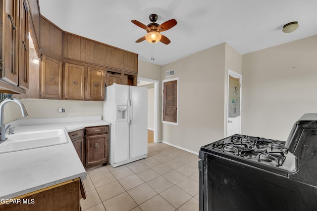 2312 Grant Ave, El Paso, TX 79930 - kitchen with white fridge with ice dispenser, black gas range oven, a sink, ceiling fan, and light tile patterned floors