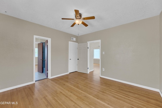 2312 Grant Ave, El Paso, TX 79930 - unfurnished bedroom featuring baseboards, light wood finished floors, multiple windows, ceiling fan, and a textured ceiling