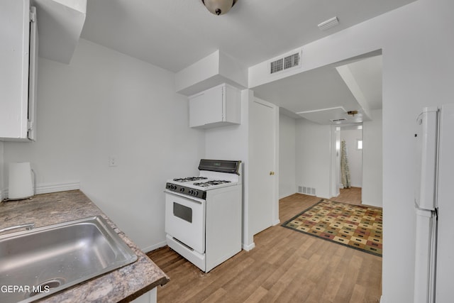 2312 Grant Ave, El Paso, TX 79930 - kitchen featuring white appliances, light wood-type flooring, white cabinetry, a sink, and baseboards