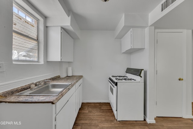 2312 Grant Ave, El Paso, TX 79930 - kitchen featuring white gas stove, a sink, dark wood-style flooring, and white cabinets
