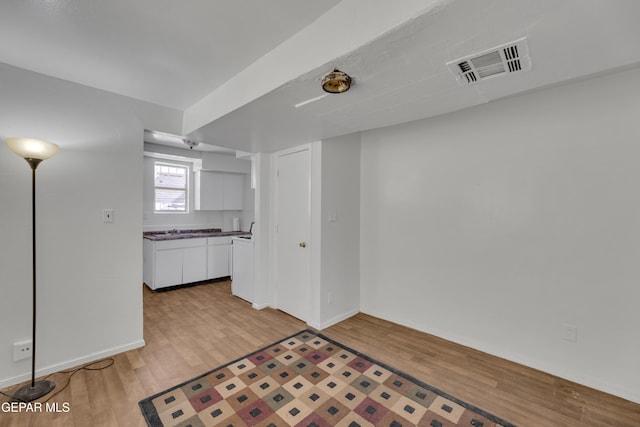 2312 Grant Ave, El Paso, TX 79930 - kitchen featuring light wood-type flooring, white cabinetry, baseboards, a sink, and dark countertops