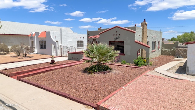 2312 Grant Ave, El Paso, TX 79930 - mediterranean / spanish-style house featuring stucco siding, a gate, and a chimney