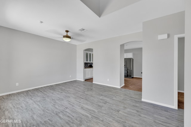 14378 N Cave Dr, El Paso, TX 79938 - unfurnished living room featuring wood finished floors, arched walkways, a ceiling fan, and baseboards