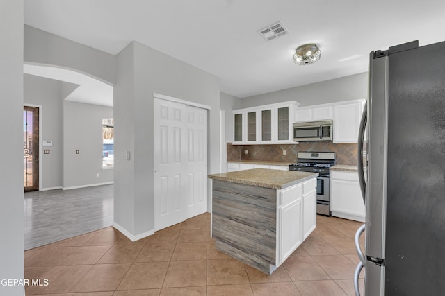 14378 N Cave Dr, El Paso, TX 79938 - kitchen with appliances with stainless steel finishes, decorative backsplash, white cabinets, glass insert cabinets, and light tile patterned flooring