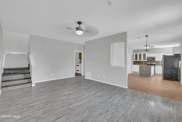 14378 N Cave Dr, El Paso, TX 79938 - unfurnished living room featuring a ceiling fan, stairway, light wood-style floors, baseboards, and a chandelier