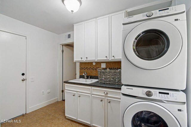 6006 Balcones Ct Unit 19, El Paso, TX 79912 - laundry area with stacked washer / drying machine, cabinet space, light tile patterned floors, and baseboards