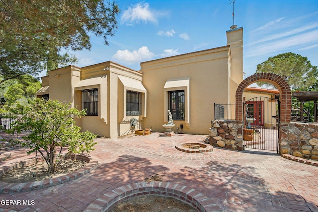 6006 Balcones Ct Unit 19, El Paso, TX 79912 - back of house featuring stucco siding, a gate, and a chimney
