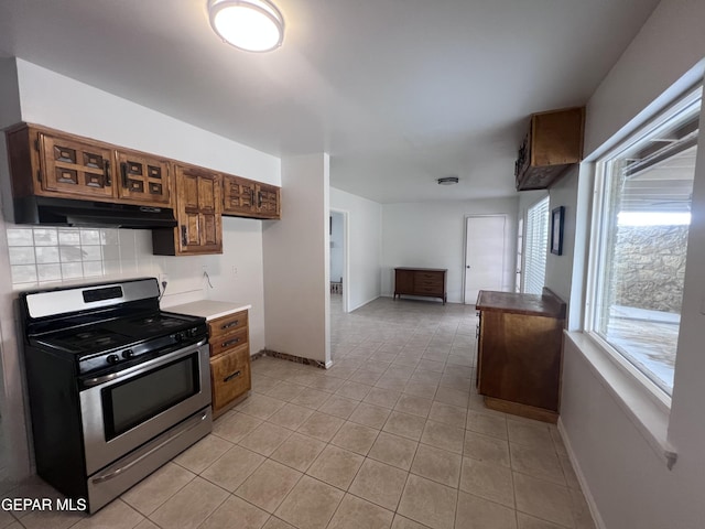 318 Olivia Cir, El Paso, TX 79912 - kitchen featuring gas range, under cabinet range hood, tasteful backsplash, light tile patterned flooring, and baseboards