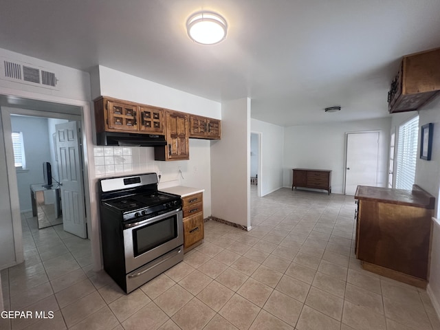 318 Olivia Cir, El Paso, TX 79912 - kitchen with stainless steel gas range, range hood, light tile patterned flooring, light countertops, and decorative backsplash