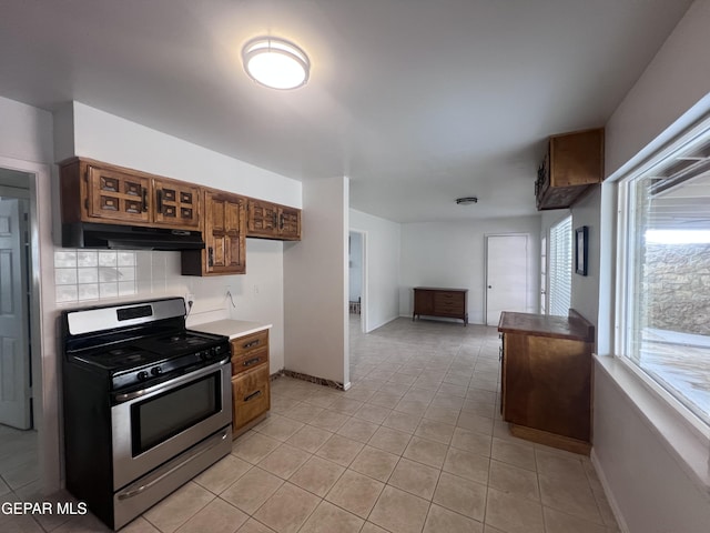 318 Olivia Cir, El Paso, TX 79912 - kitchen featuring stainless steel gas range, exhaust hood, tasteful backsplash, light tile patterned floors, and baseboards